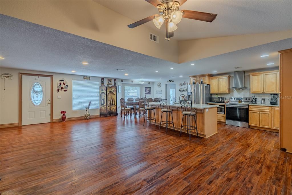 An open-concept kitchen and living area features wood flooring, a center island, and vaulted ceilings — 18853 TRACER DRIVE, LUTZ, FL