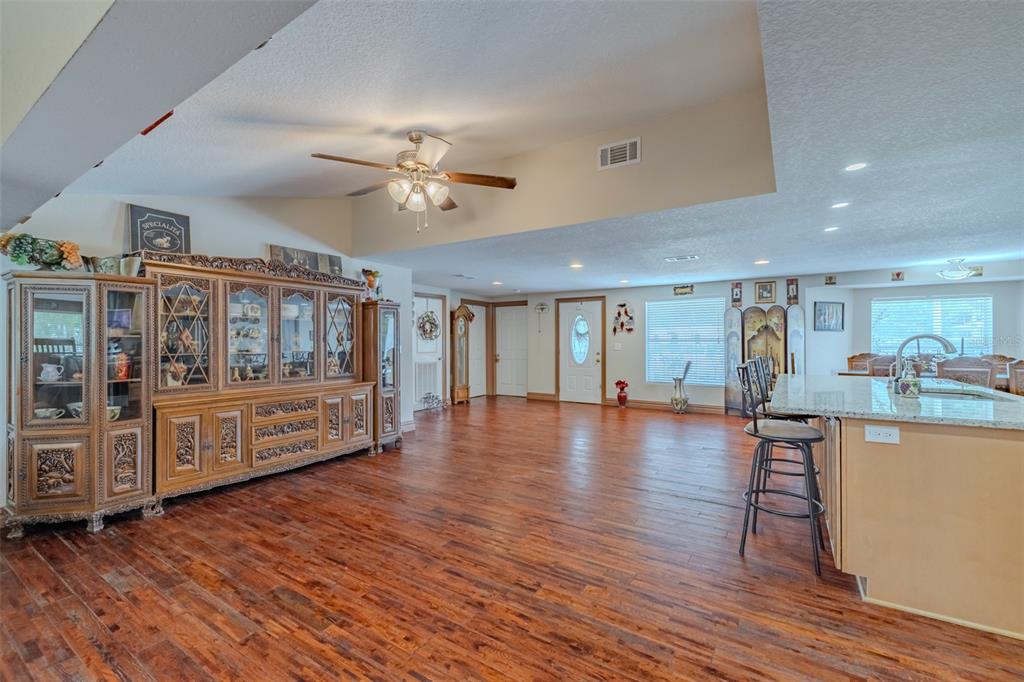 A spacious living area features wood flooring, a large china cabinet, and a kitchen island — 18853 TRACER DRIVE, LUTZ, FL