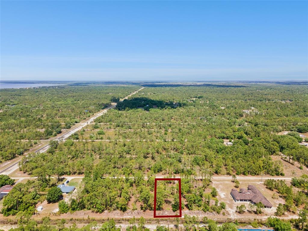 An aerial view shows a rectangular plot of land outlined in red amidst wooded terrain — 3871 GALLARDIA DRIVE, INDIAN LAKE ESTATES, FL