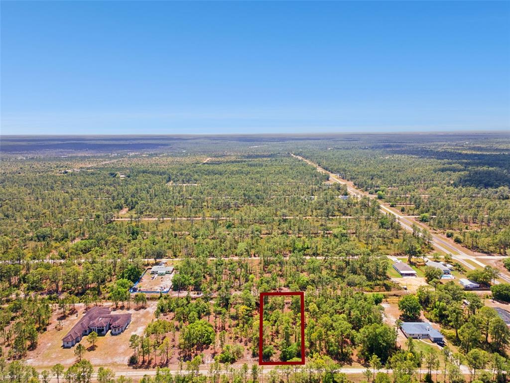An aerial view shows a rectangular plot of land outlined in red amidst wooded terrain — 3871 GALLARDIA DRIVE, INDIAN LAKE ESTATES, FL