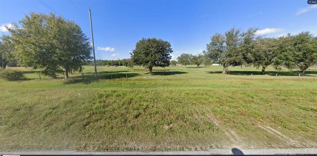 A wide, grassy, undeveloped lot features several mature trees and a wire fence — OLD GRADE RD, POLK CITY, FL
