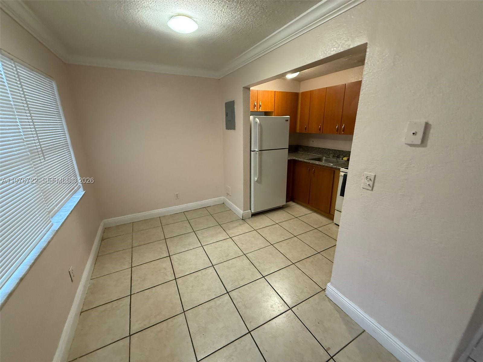 A kitchen with light-colored tile flooring, wooden cabinets, and a white refrigerator — 4732 SW 33rd Ave # 103, Dania Beach FL 33312, DANIA BEACH, FL