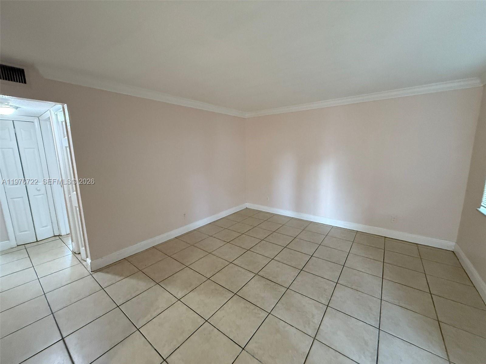 An empty room features light-colored walls, white crown molding, and beige tile flooring — 4732 SW 33rd Ave # 103, Dania Beach FL 33312, DANIA BEACH, FL