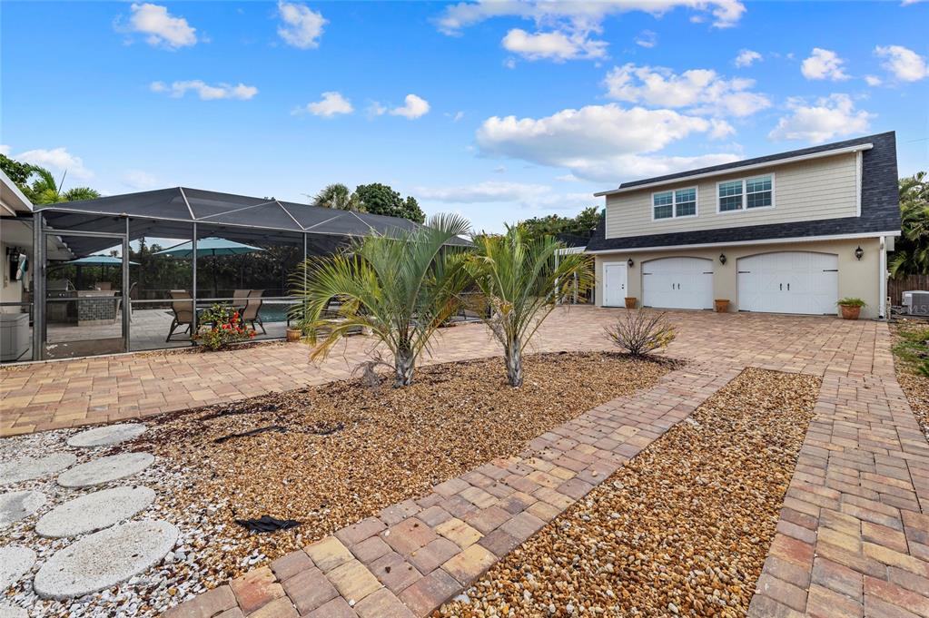 A paved driveway leads to a two-story garage building next to a screened-in pool area — 6139 HOLLYWOOD BOULEVARD, SARASOTA, FL