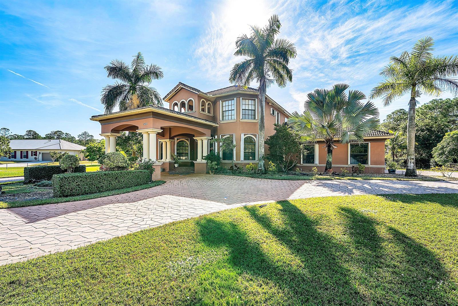 A two-story stucco house with a porte-cochère, palm trees, and a paved driveway — 17560 69th Street N, FL 33470, FL
