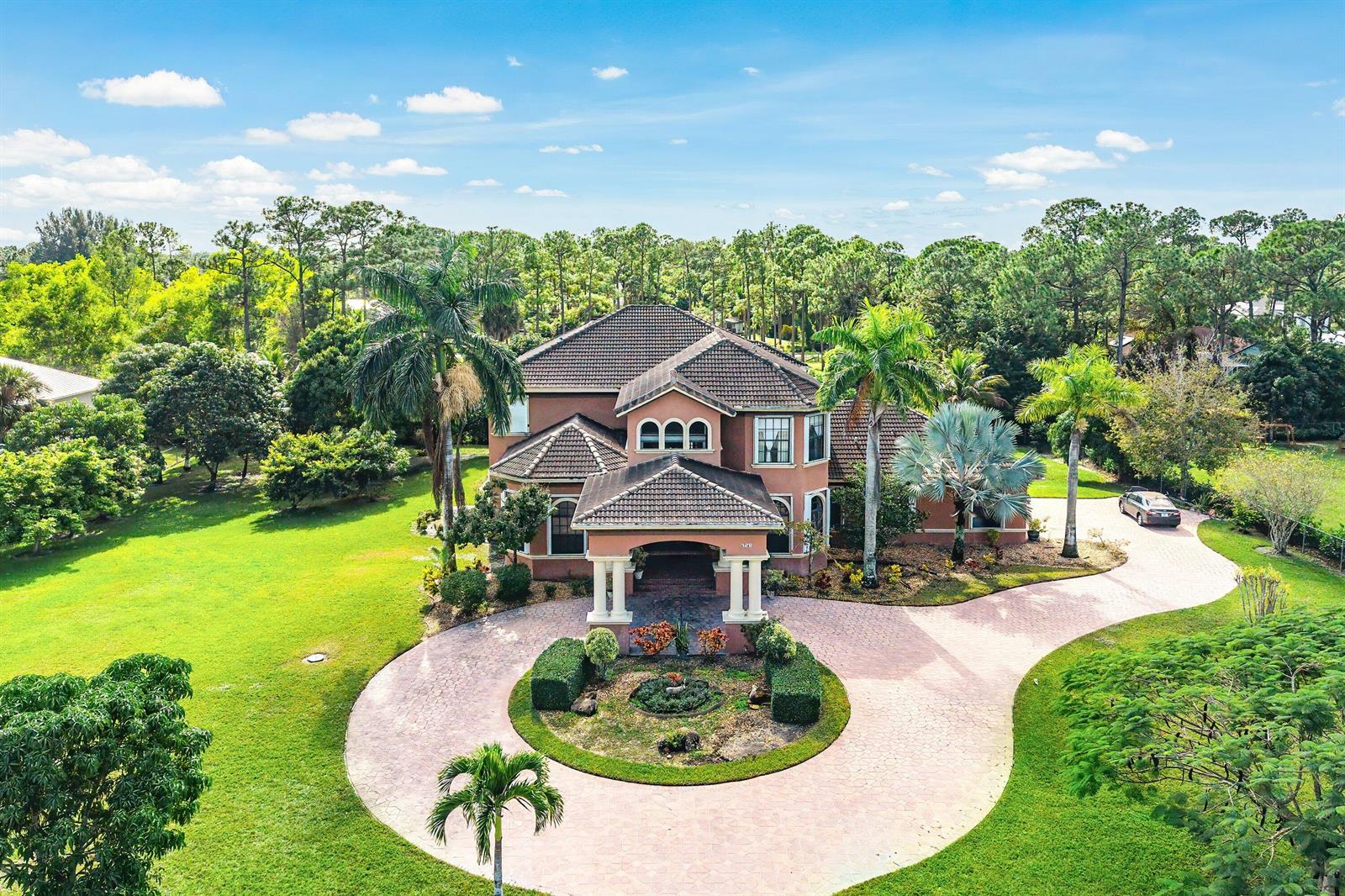 An aerial view of a two-story house with a circular driveway and lush landscaping — 17560 69th Street N, FL 33470, FL
