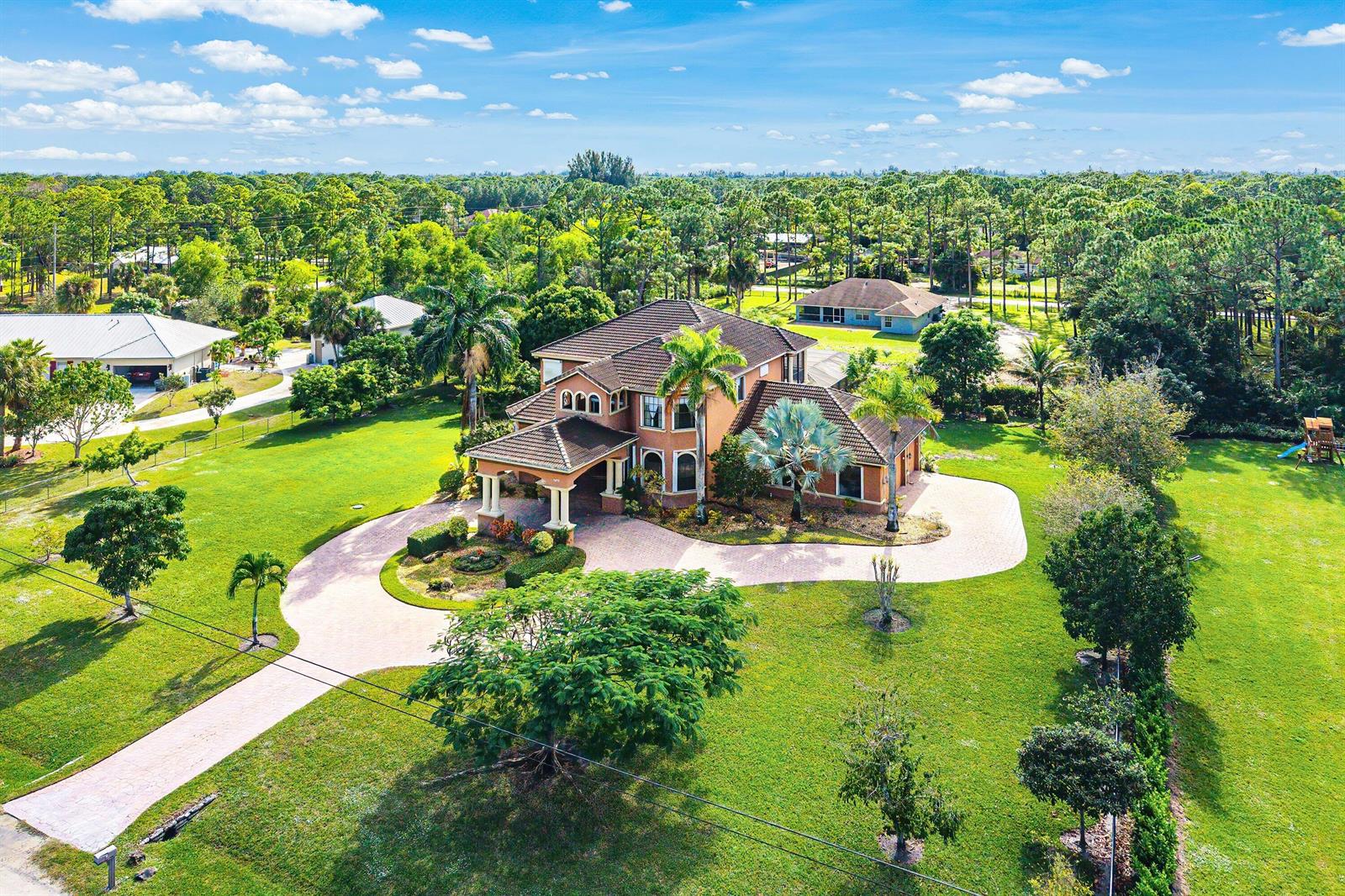 An aerial view shows a two-story house with a circular driveway and large grassy yard — 17560 69th Street N, FL 33470, FL