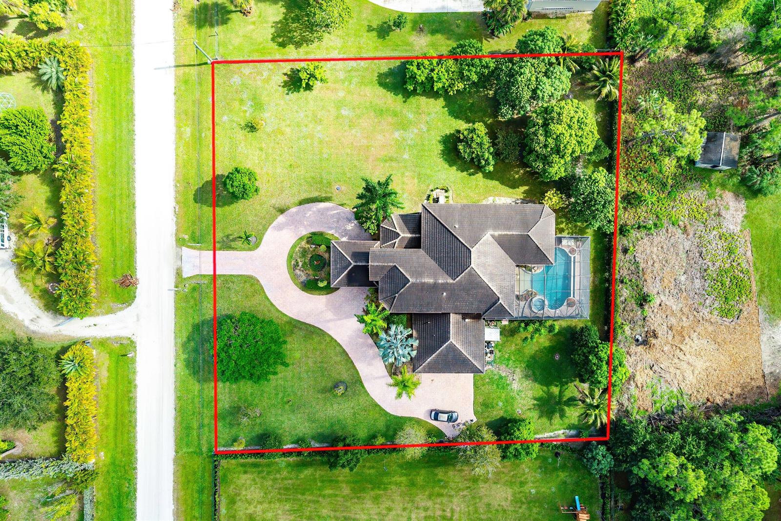 An aerial view shows a house with a pool and circular driveway on a large lot — 17560 69th Street N, FL 33470, FL