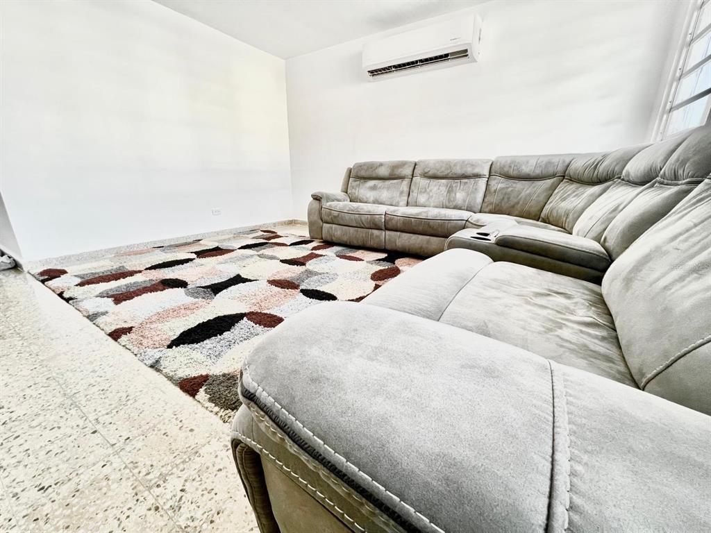 A living room features a large gray sectional sofa, a patterned area rug, and air conditioning — J39 URB.VILLA ANDALUCIA CALLE GAUCIN, SAN JUAN, PR
