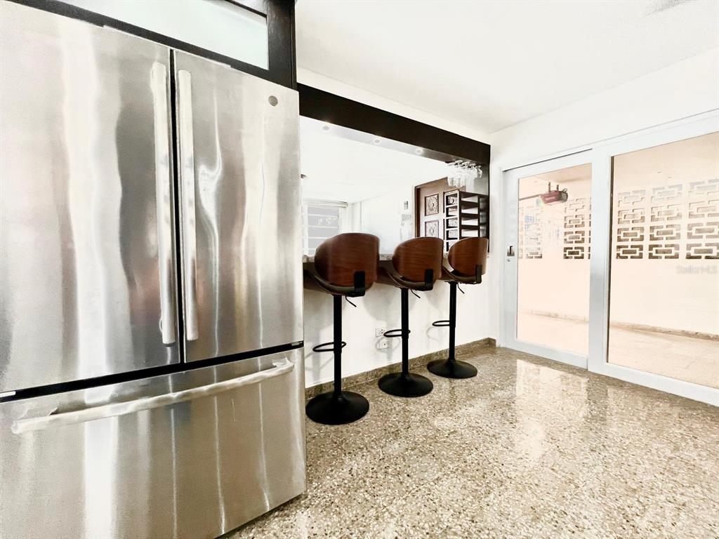 A kitchen features a stainless steel refrigerator, a breakfast bar with three stools, and terrazzo flooring — J39 URB.VILLA ANDALUCIA CALLE GAUCIN, SAN JUAN, PR