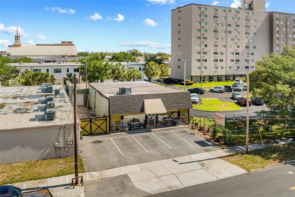 An aerial view shows a single-story commercial building with a parking lot and adjacent apartments — 155 AVENUE B SW, WINTER HAVEN, FL