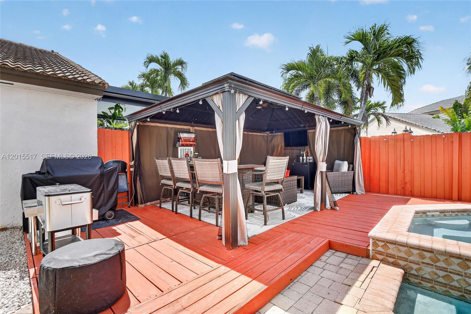 A backyard deck features a covered gazebo with outdoor seating next to a small pool — 14630 Cedar Creek Pl, Davie FL 33325, DAVIE, FL