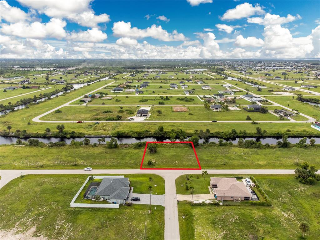 An aerial view shows a vacant rectangular lot outlined in red, situated across from two houses — 3902 NW 41ST LANE, CAPE CORAL, FL