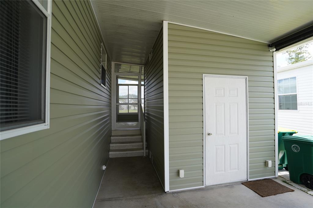 A covered outdoor entryway features green vinyl siding, a white door, and stairs leading upward — 14510 COSTINE COURT, PORT CHARLOTTE, FL