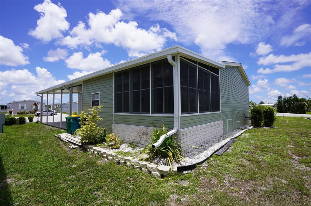 A light green mobile home features a screened-in porch and a concrete block foundation — 14510 COSTINE COURT, PORT CHARLOTTE, FL