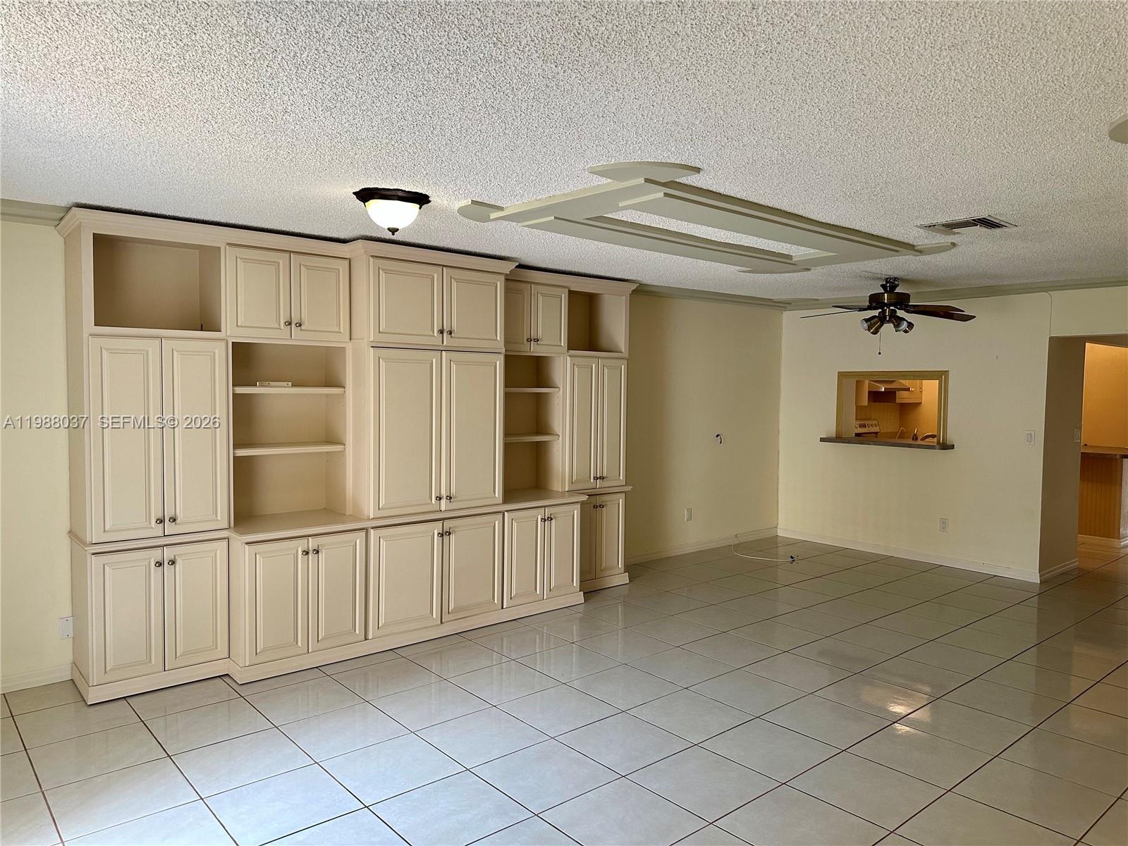 A living room features large built-in cabinetry, tile flooring, and a ceiling fan — 13705 SW 84th St # F, Miami FL 33183, MIAMI, FL