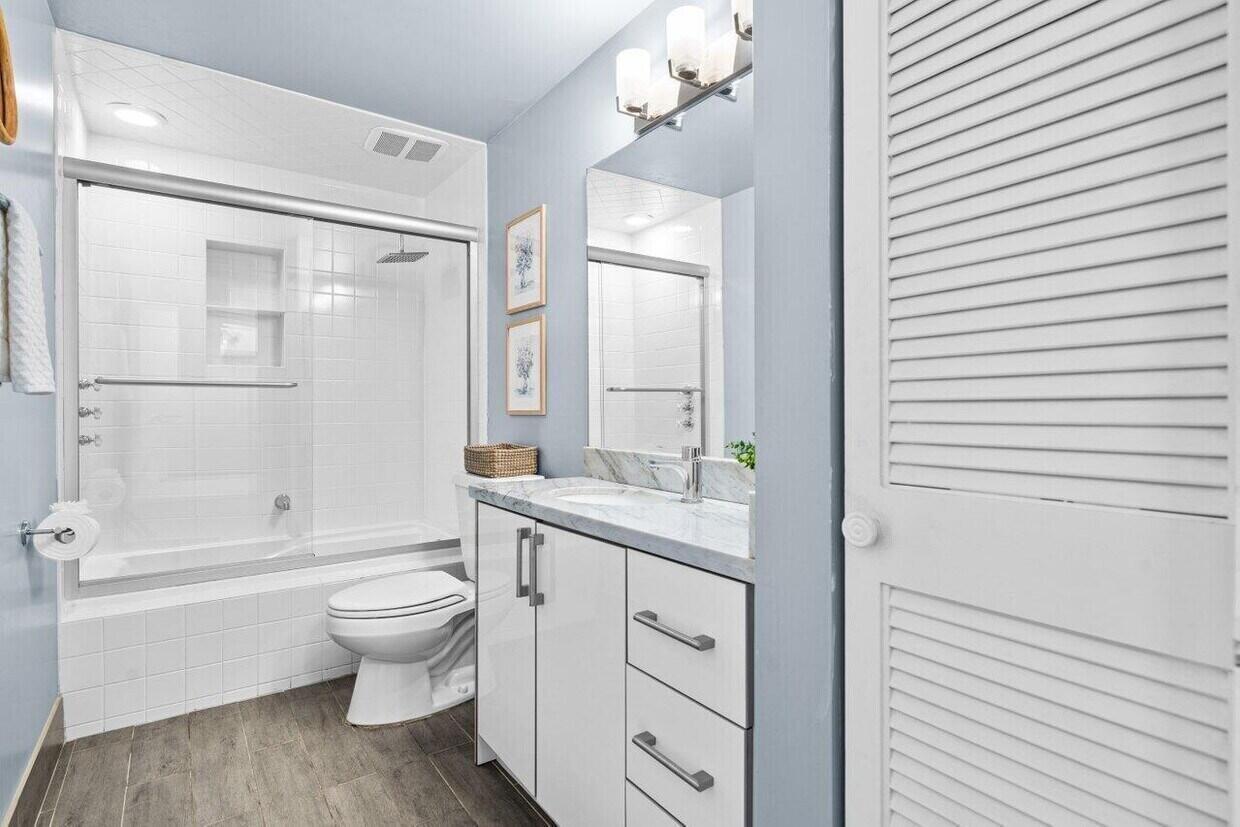 A bathroom features a white vanity, a tiled shower-tub combination, and light blue walls — 419 E Atlantic Avenue, Delray Beach FL 33483, DELRAY BEACH, FL
