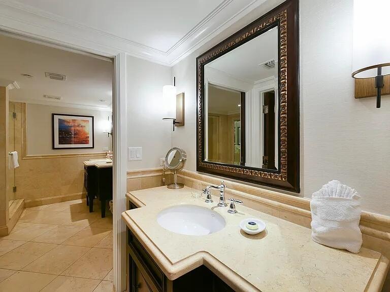 A bathroom features a stone vanity, a framed mirror, and a doorway to a shower — 81801 Overseas Highway Highway # 714, Islamorada FL 33036, ISLAMORADA, FL