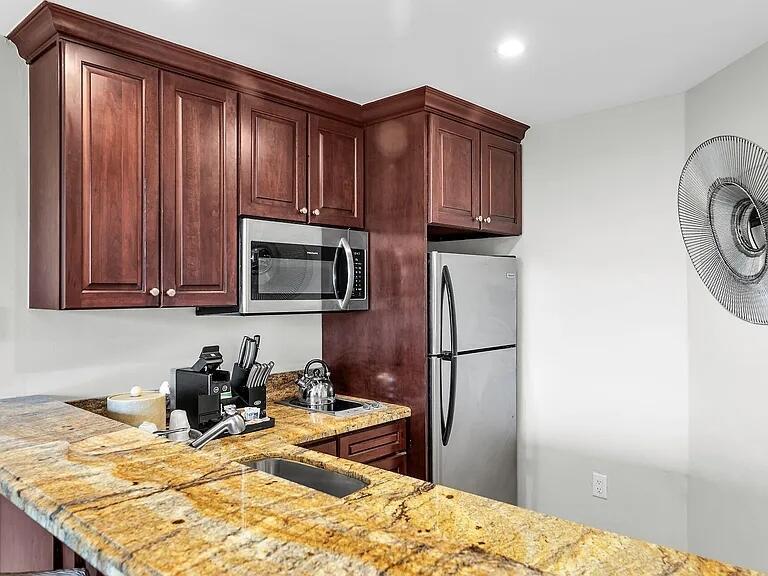 A kitchen features dark wood cabinets, granite countertops, stainless steel appliances, and a wall fan — 81801 Overseas Highway Highway # 714, Islamorada FL 33036, ISLAMORADA, FL