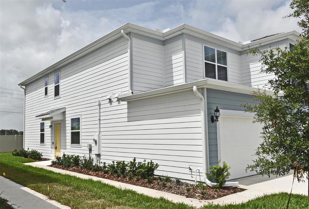 A two-story house with light gray horizontal siding, a white garage door, and a yellow door — 3101 EMERALD ACRES LANE, SANFORD, FL