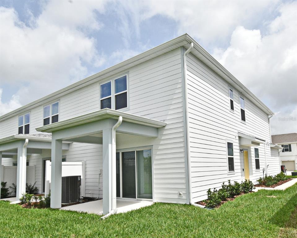 The exterior of a two-story white vinyl-sided townhouse features a covered patio and sliding doors — 3101 EMERALD ACRES LANE, SANFORD, FL