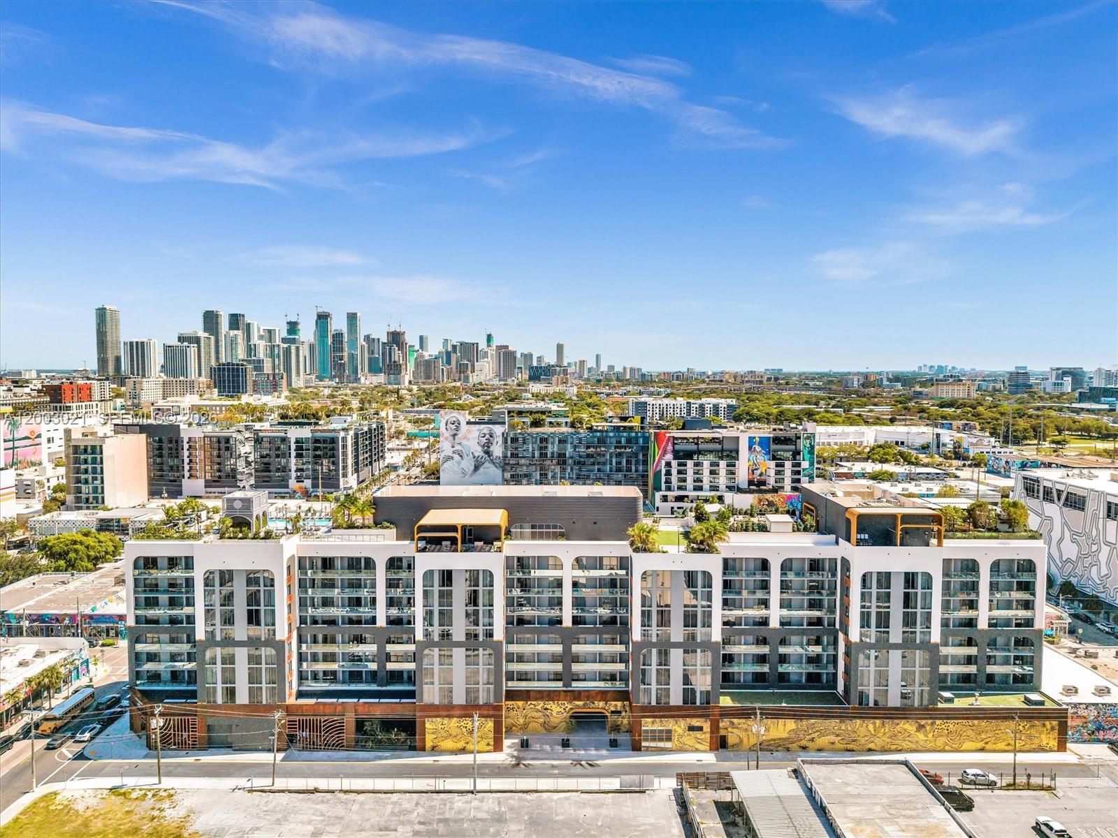 An aerial view of a modern multi-story apartment building with a mural-adorned ground floor — 2700 NW 2nd Ave # 439, Miami FL 33127, MIAMI, FL