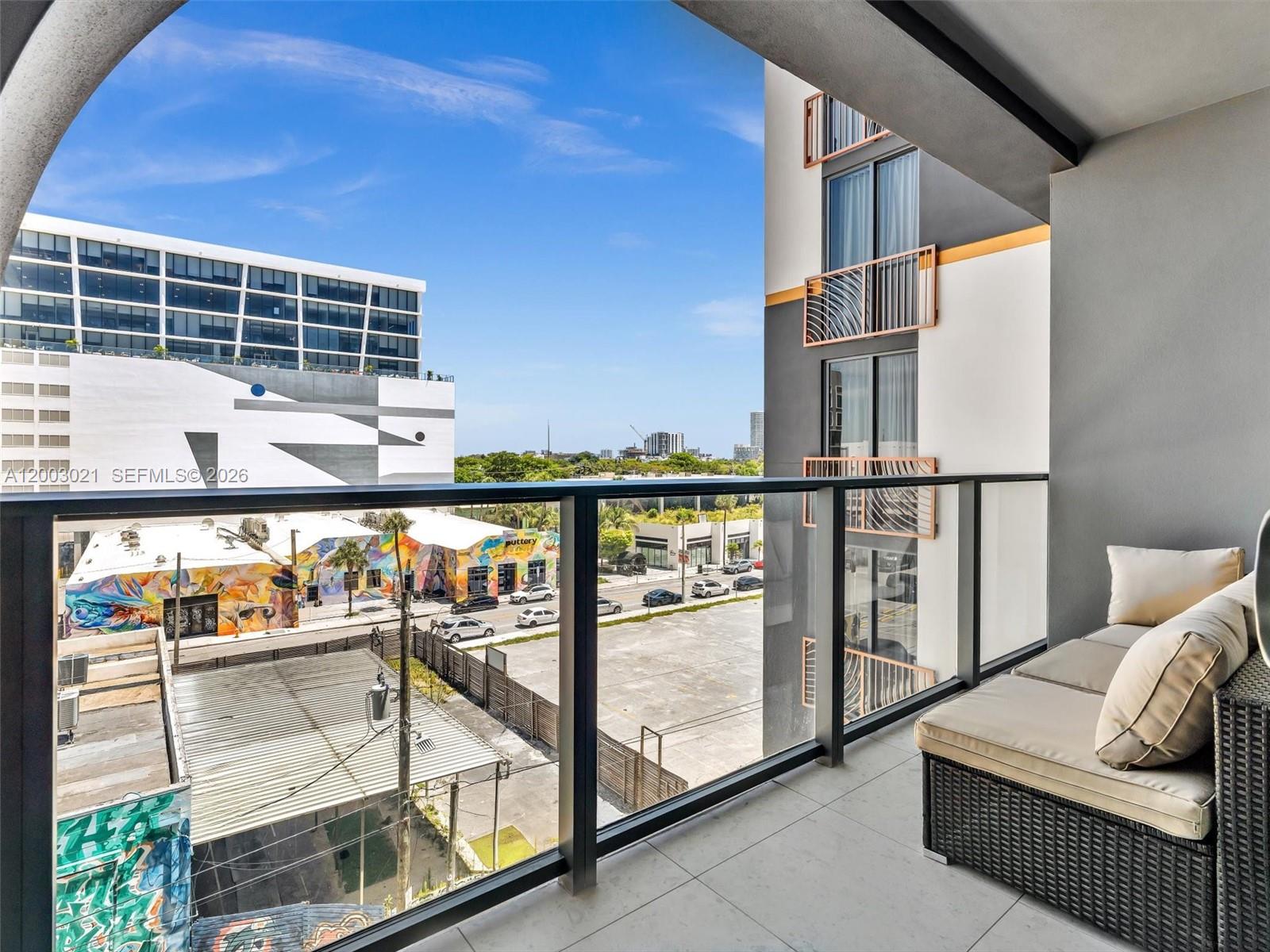 A balcony with outdoor seating overlooks a city street, parking lot, and nearby buildings — 2700 NW 2nd Ave # 439, Miami FL 33127, MIAMI, FL