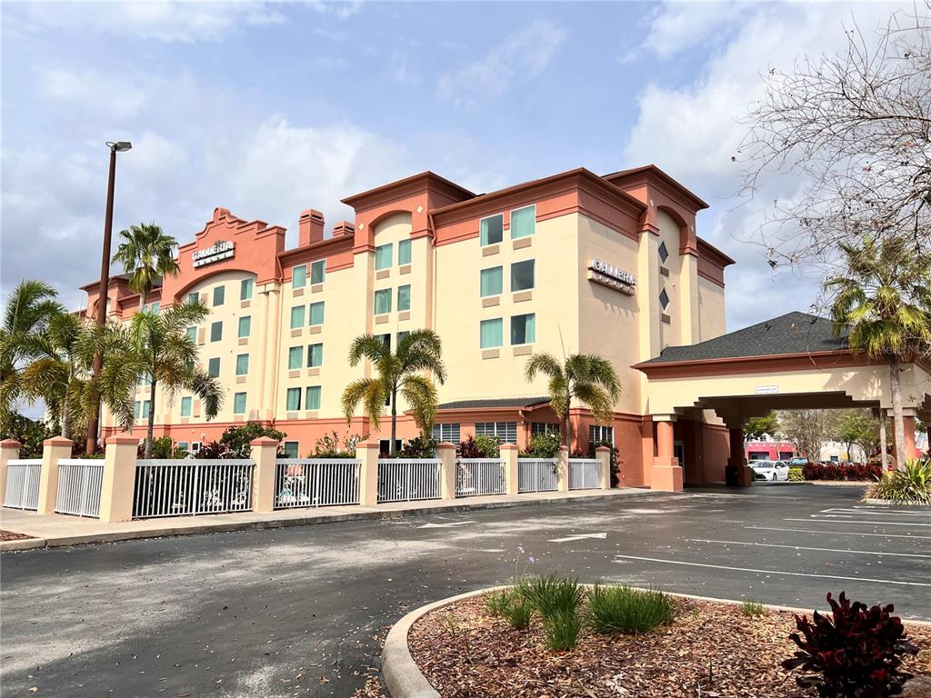 A multi-story hotel building with a tan facade, orange trim, and a covered entrance — 3000 MAINGATE LANE UNIT 212, KISSIMMEE, FL