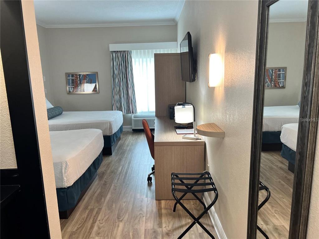 A hotel room features two beds, a desk with a chair, and a wall-mounted mirror — 3000 MAINGATE LANE UNIT 212, KISSIMMEE, FL