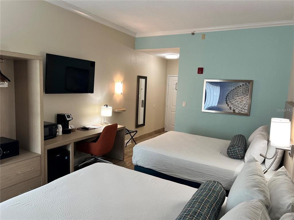 A hotel room features two beds, a desk, a television, and a light blue wall — 3000 MAINGATE LANE UNIT 212, KISSIMMEE, FL