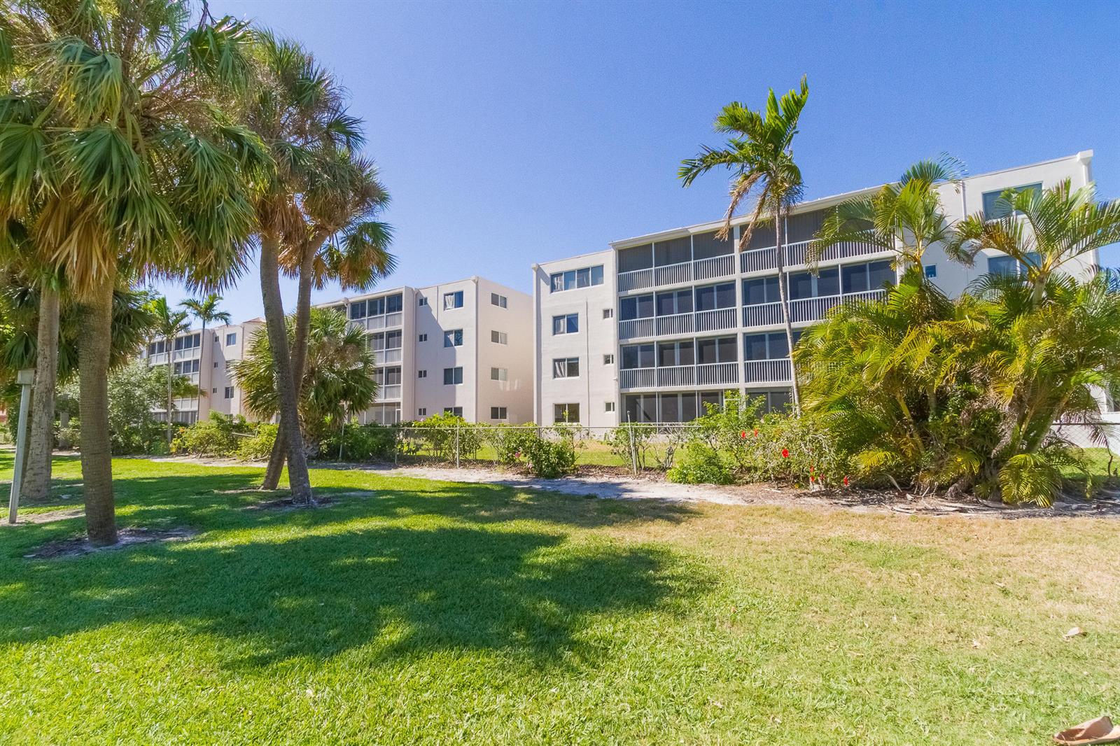 Exterior view of two multi-story apartment buildings surrounded by palm trees and a grassy lawn — 300 E Royal Palm Road # 0420, Boca Raton FL 33432, BOCA RATON, FL