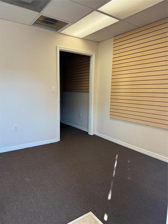 An empty office room features brown carpet, white walls, and a wood-paneled display wall — 4022 LAND O LAKES BOULEVARD UNIT 101, LAND O LAKES, FL