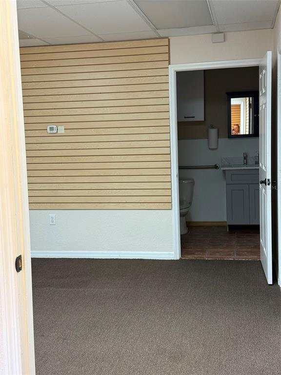 A room with a slat wall and carpeted floor leads into a small bathroom — 4022 LAND O LAKES BOULEVARD UNIT 101, LAND O LAKES, FL