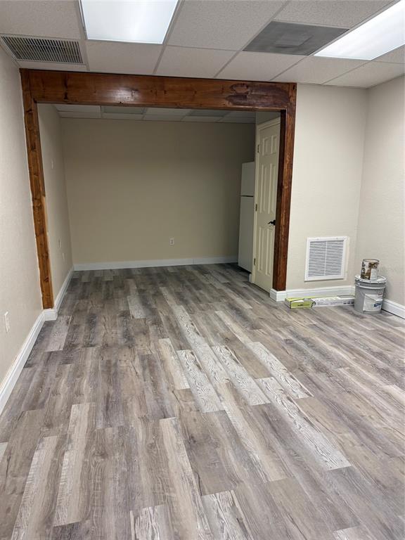 An interior room features wood-look vinyl flooring, a dark wood-trimmed doorway, and a drop ceiling — 4022 LAND O LAKES BOULEVARD UNIT 101, LAND O LAKES, FL