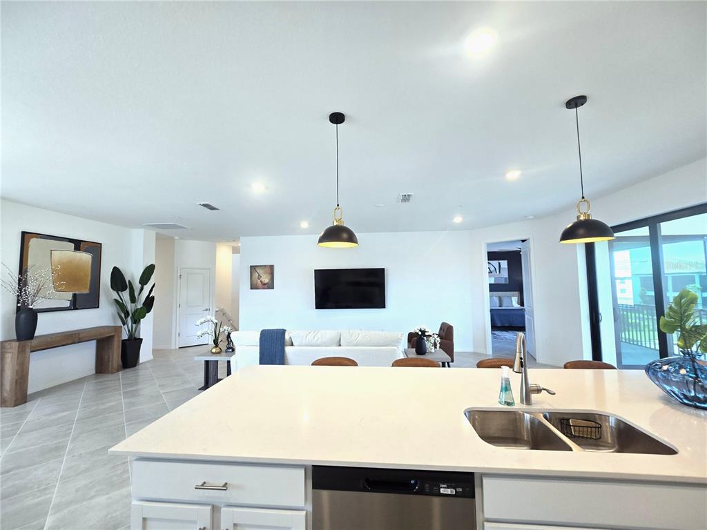 A modern kitchen features white cabinetry, a large quartz island, and four brown bar stools — 5552 SUMMIT POINTE CIRCLE UNIT #103, BRADENTON, FL