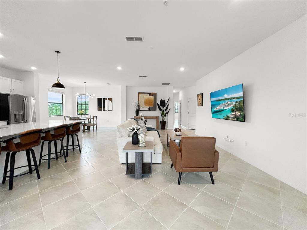 A kitchen island with a double sink overlooks an open-concept living room with white walls — 5552 SUMMIT POINTE CIRCLE UNIT #103, BRADENTON, FL