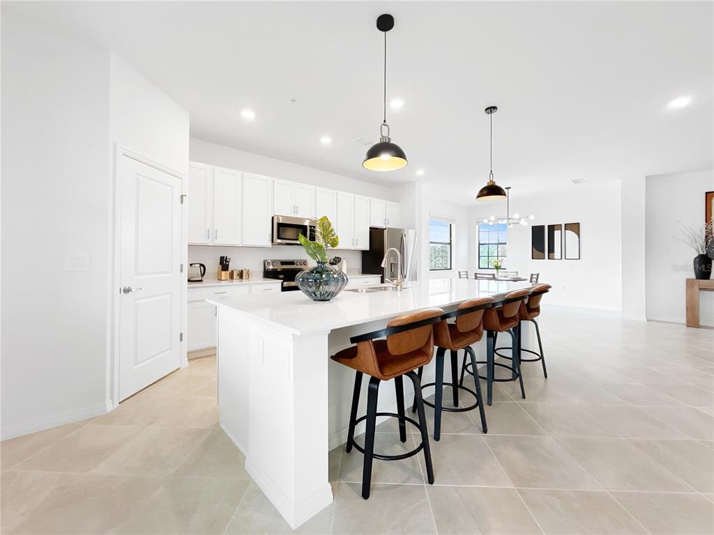 An open-concept living room and kitchen feature tile flooring, a large island, and neutral walls — 5552 SUMMIT POINTE CIRCLE UNIT #103, BRADENTON, FL