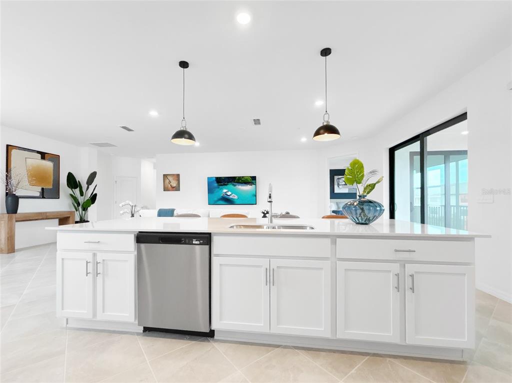 A white kitchen island with a stainless steel dishwasher sits in a bright open-concept room — 5552 SUMMIT POINTE CIRCLE UNIT #103, BRADENTON, FL