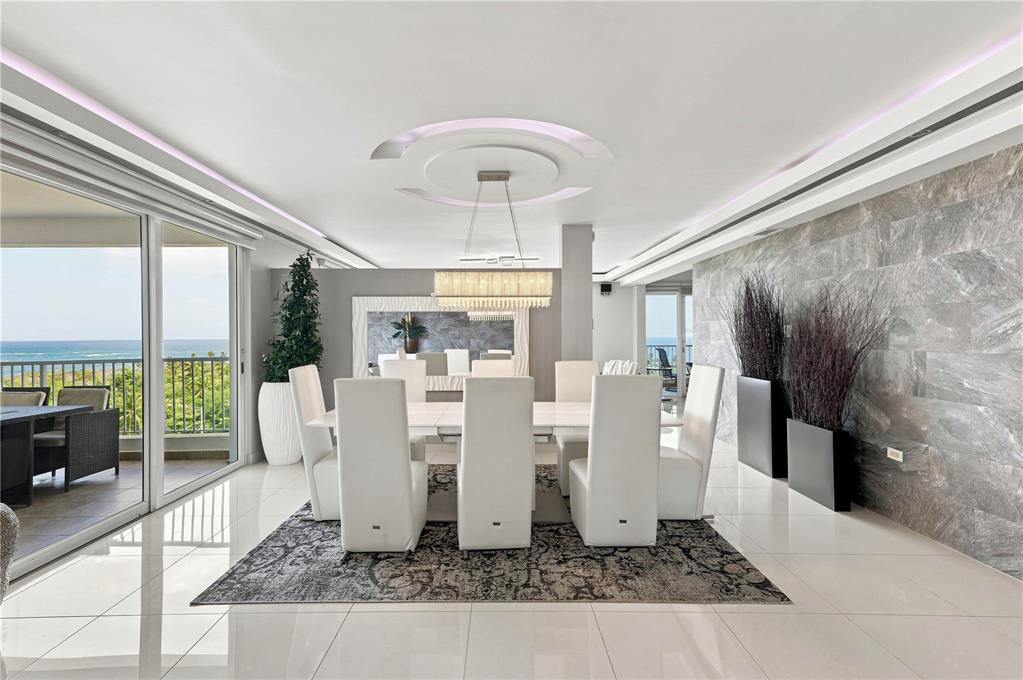 A modern dining room features white chairs, a rectangular table, and a stone accent wall — 145 OLIVINE STREET UNIT PH-571, VEGA ALTA, PR