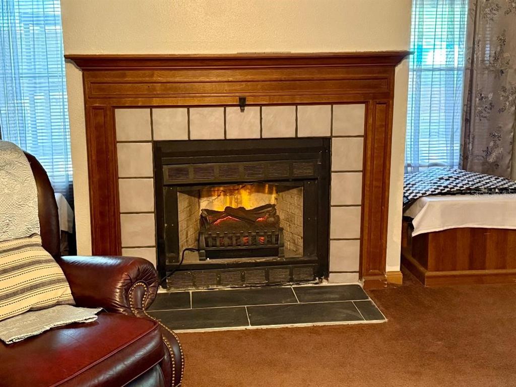 A living room features a fireplace with a wood mantel and light-colored square tile surround — 11340 SW 28TH WAY, WEBSTER, FL
