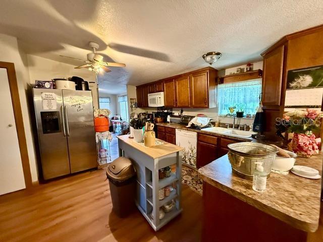 A kitchen features wood cabinets, stainless steel appliances, a center island, and wood-look flooring — 11340 SW 28TH WAY, WEBSTER, FL