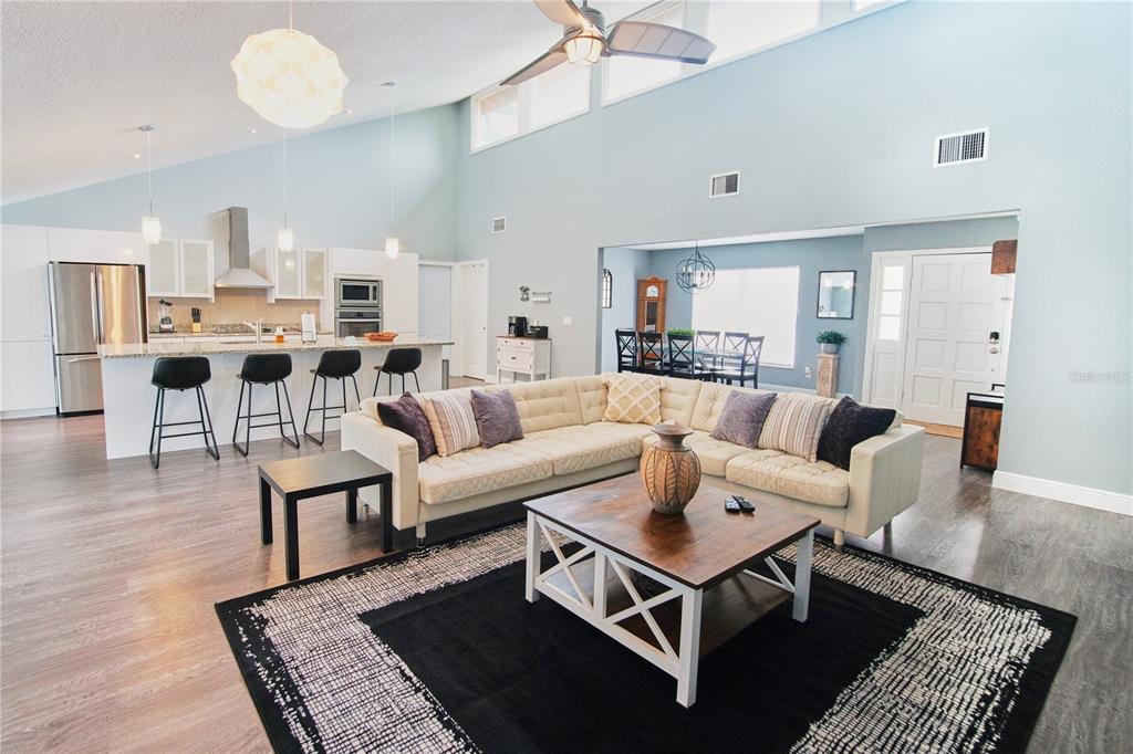 A spacious open-concept living room and kitchen with light blue walls and wood-look flooring — 5417 PITCH PINE DRIVE, ORLANDO, FL