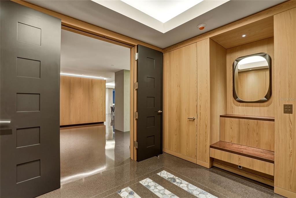 A modern entryway features dark doors, light wood paneling, a built-in bench, and stone flooring — 400 BEACH DRIVE NE UNIT 2605, ST PETERSBURG, FL