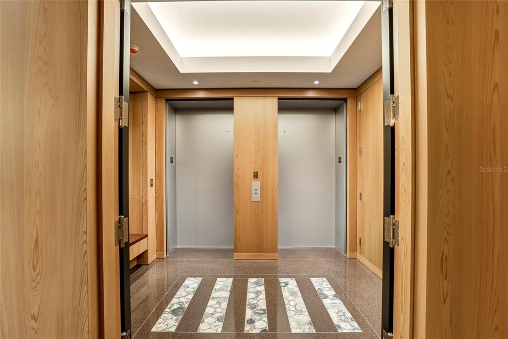 An elevator lobby features light wood paneling, stone floor inlays, and recessed ceiling lighting — 400 BEACH DRIVE NE UNIT 2605, ST PETERSBURG, FL