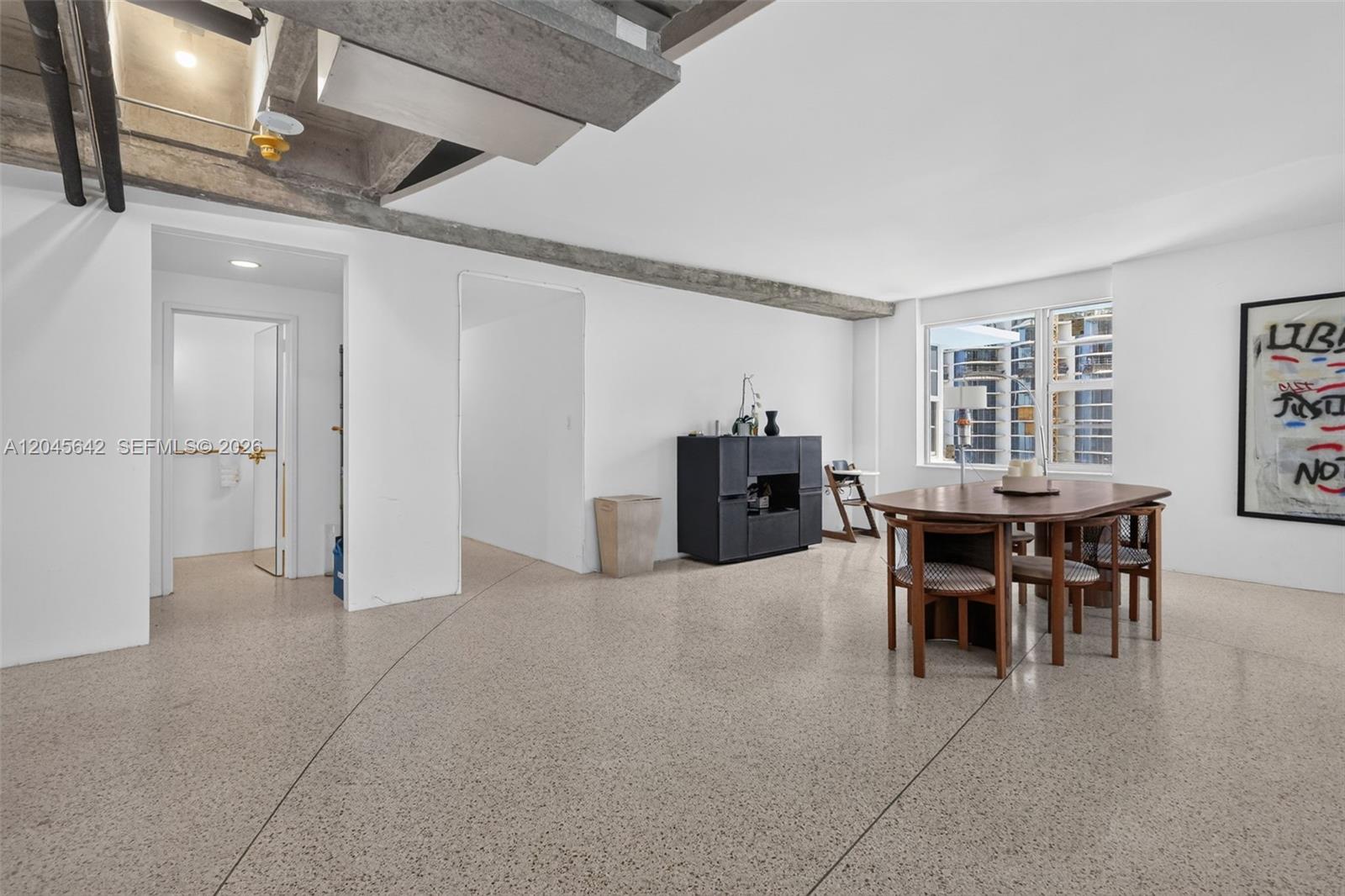 A dining area with a wooden table, chairs, and concrete flooring in an open-plan space — 5255 Collins Ave # 12E, Miami Beach FL 33140, MIAMI BEACH, FL