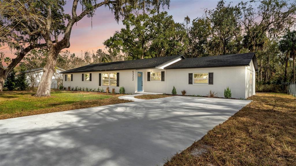 A single-story white brick house with a blue front door and a concrete driveway — 5322 FORESTBROOK DRIVE E, LAKELAND, FL