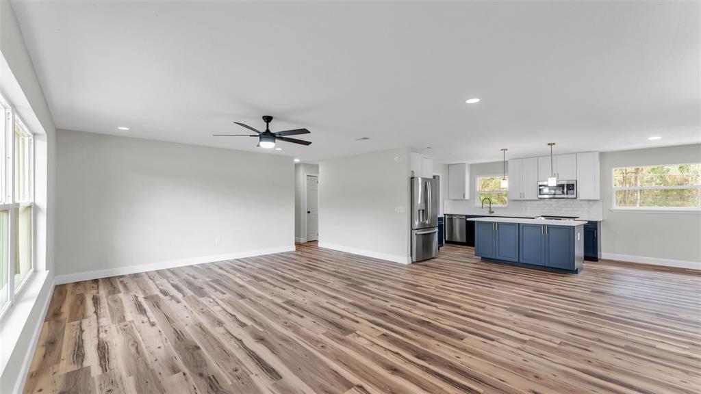 An open-concept kitchen and living area features wood-look flooring, white walls, and blue cabinetry — 5322 FORESTBROOK DRIVE E, LAKELAND, FL