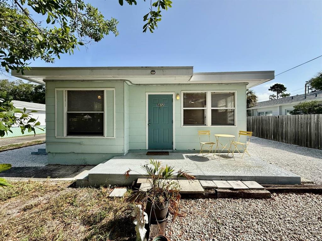 A light green single-story house features a flat roof, a teal front door, and gravel landscaping — 5612 18TH AVENUE S, ST PETERSBURG, FL