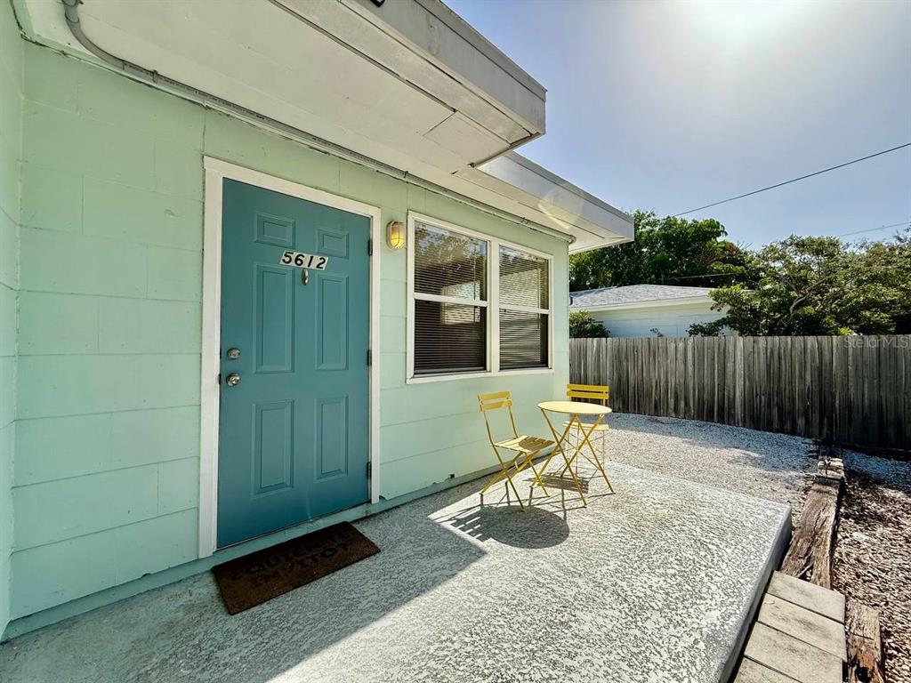 A light green exterior wall features a blue door, a window, and a small patio — 5612 18TH AVENUE S, ST PETERSBURG, FL