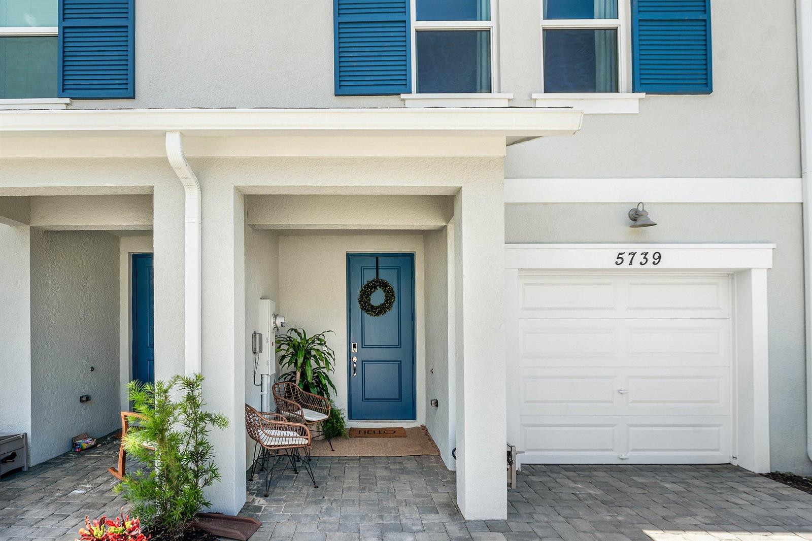 The exterior view shows a house entrance with a blue door, garage, and paved driveway — 5739 SE Edgewater Circle, Stuart FL 34997, STUART, FL